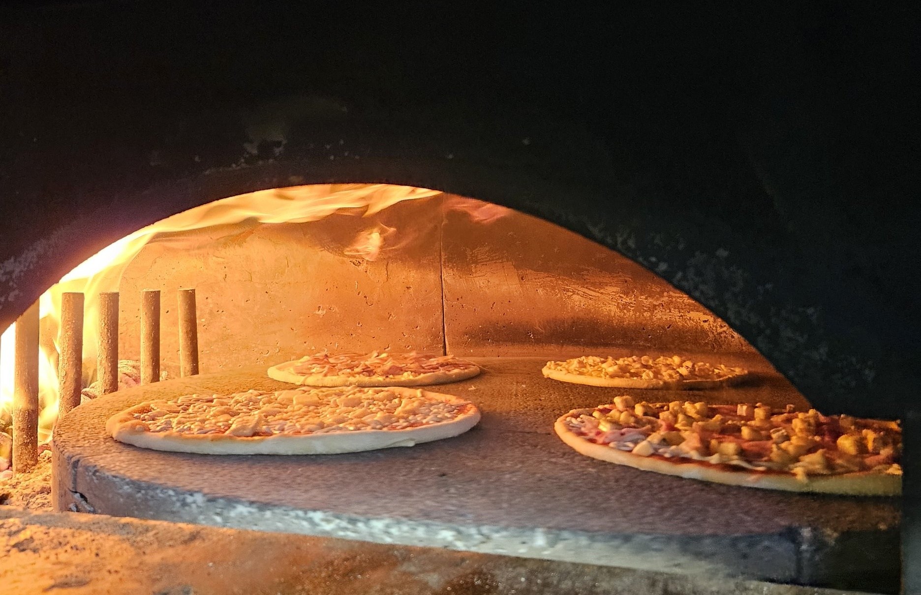Pizzas en cuisson dans le four à bois de La Coquetière